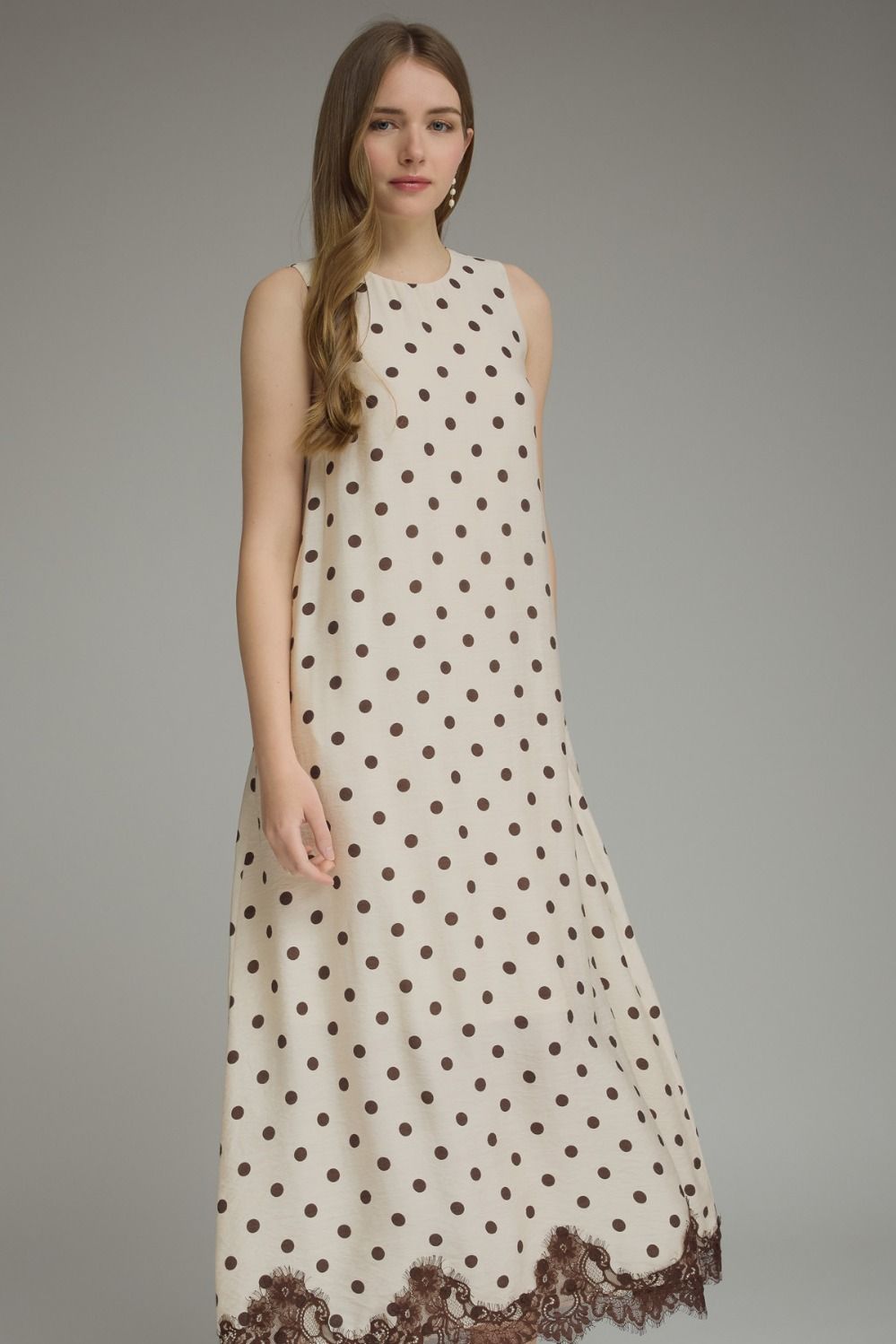 Woman wearing a polka dot dress with lace trim on a gray background