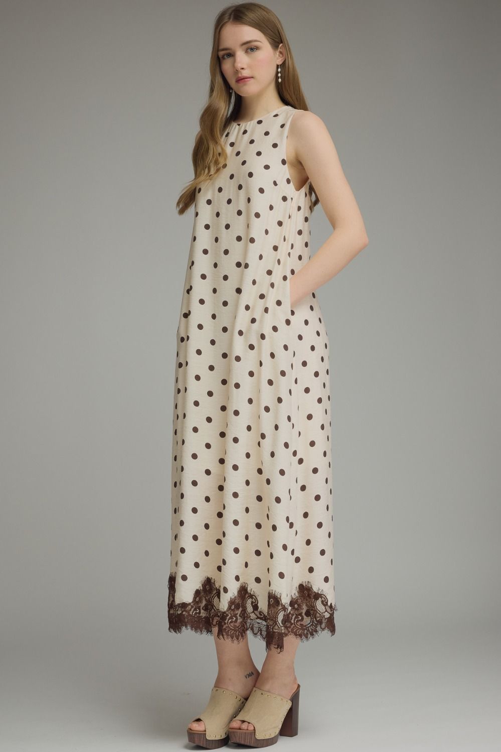 Woman wearing a polka dot dress with lace trim on a gray background