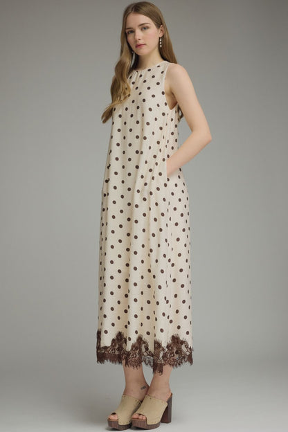 Woman wearing a polka dot dress with lace trim on a gray background