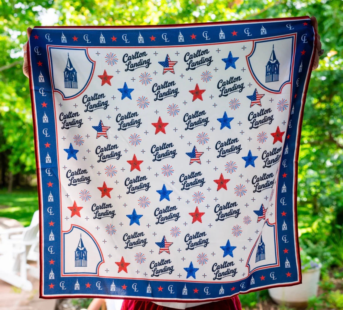 Festive silk neck scarf with star and stripe pattern, held outdoors.