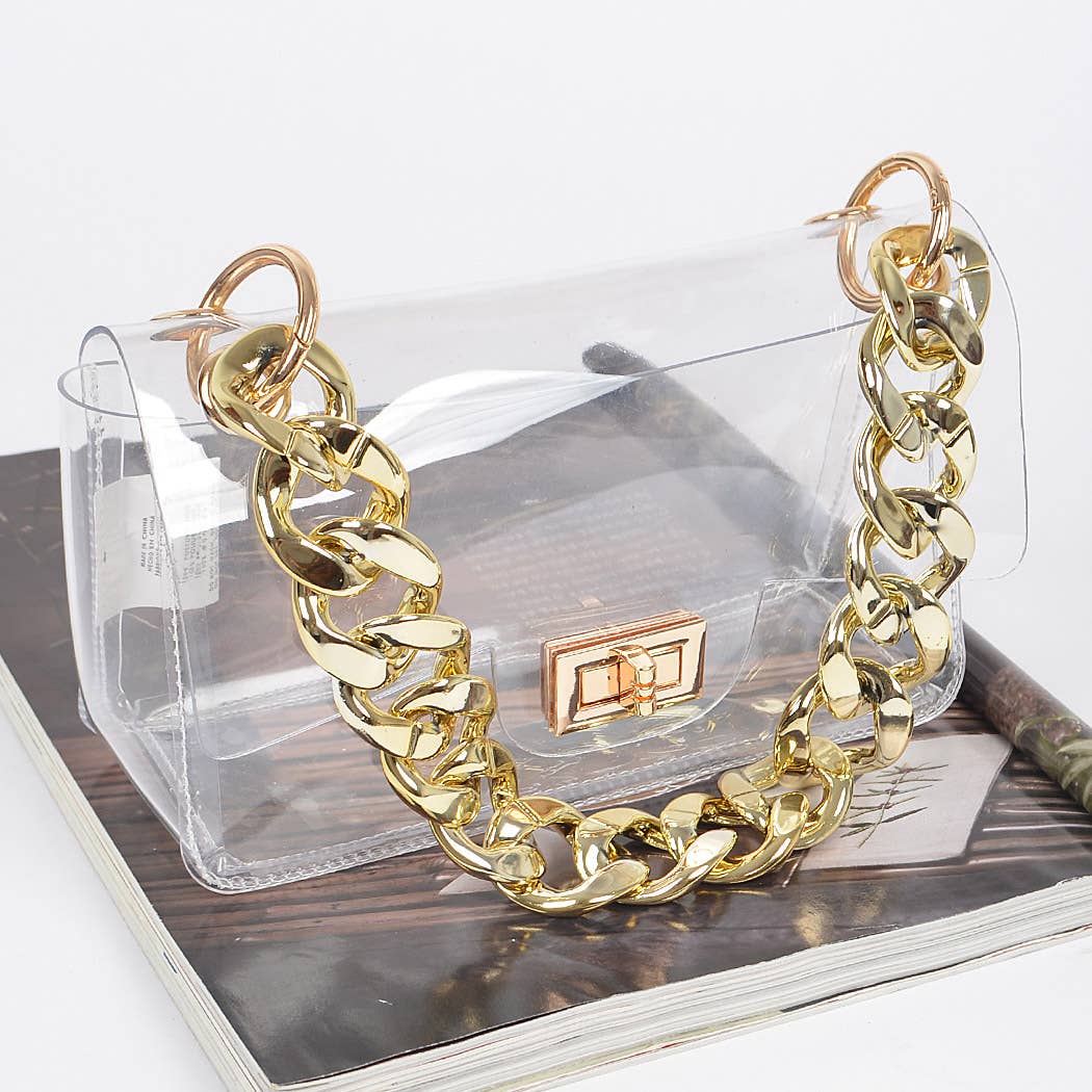 Gold chain necklace on a transparent handbag with a wooden surface underneath