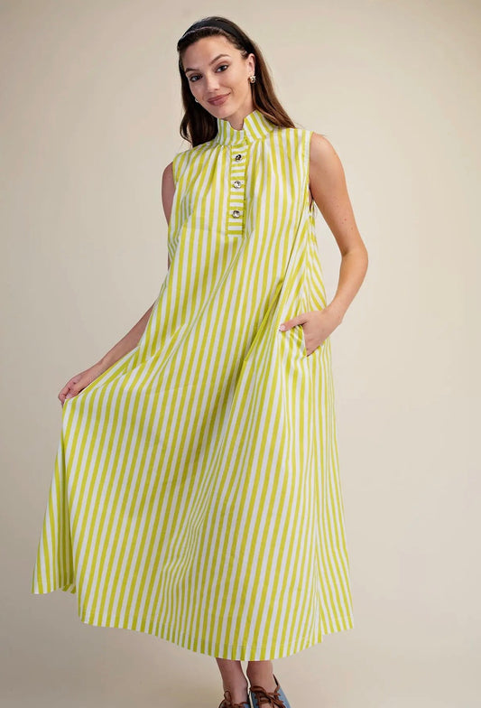 A woman modeling a sleeveless midi dress with vertical lime green and white stripes, featuring a mock neck and decorative buttons at the collar, set against a plain beige studio background.