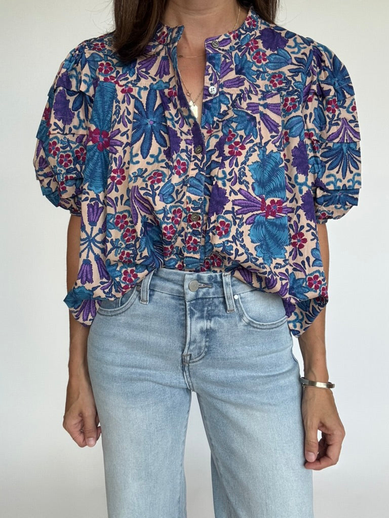 Woman wearing a short-sleeve floral print blouse with blue jeans, front view