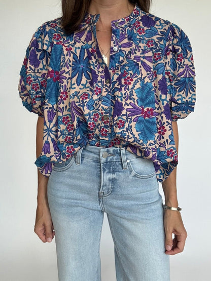 Woman wearing a short-sleeve floral print blouse with blue jeans, front view