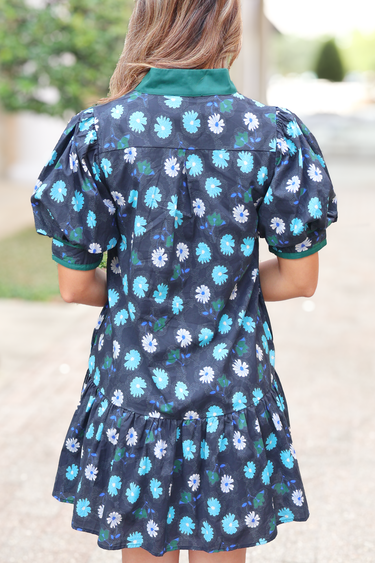 Woman wearing short floral dress with puff sleeves and green collar, outdoor setting