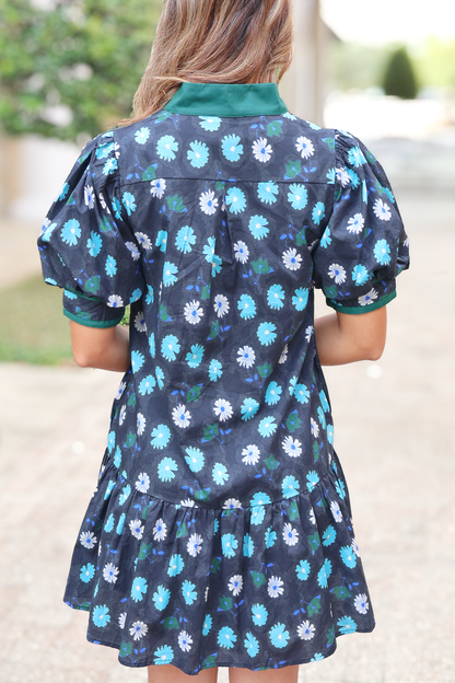 Woman wearing short floral dress with puff sleeves and green collar, outdoor setting