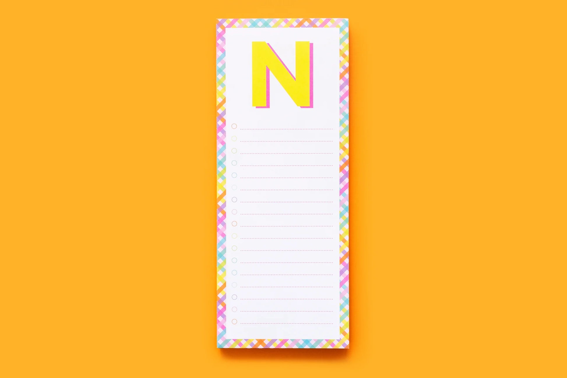 Colorful letter N notepad with checklist lines on orange background, stationery accessory
