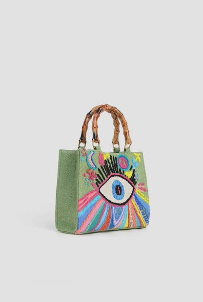 Green tote bag with bamboo handles and colorful embroidered eye and rainbow design