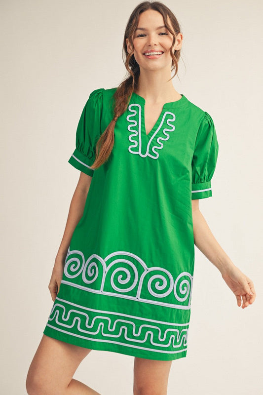 Woman wearing a green dress with white patterns on a beige background