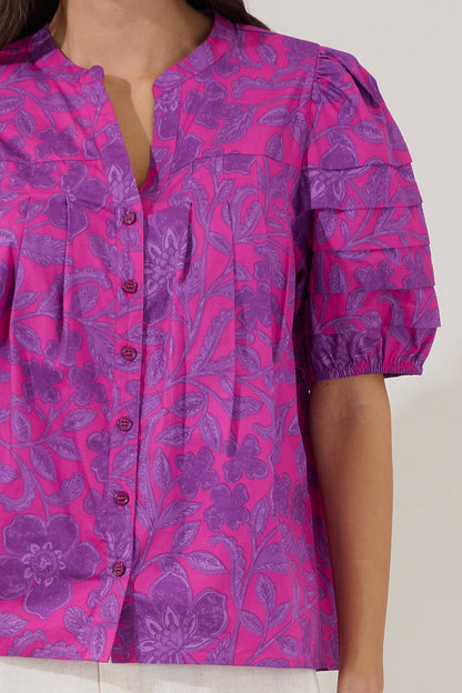 Close-up of a pink and purple floral patterned shirt on a plain background