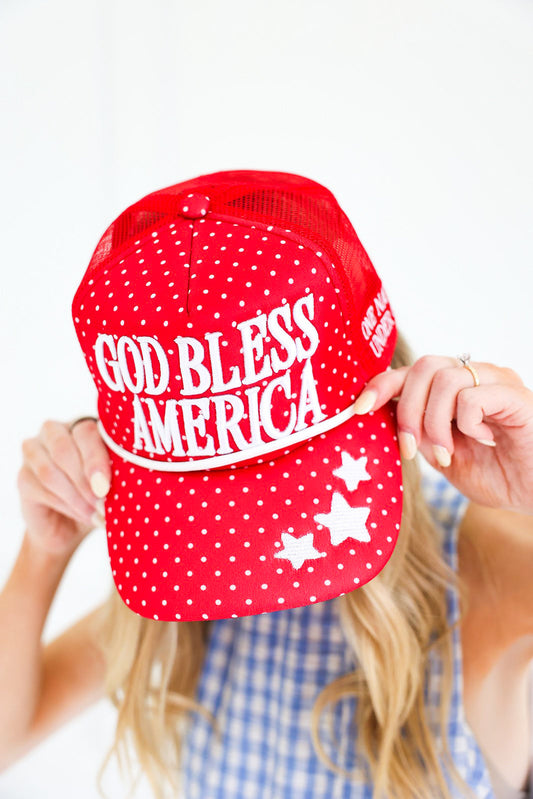 Red cap with 'God Bless America' text held by a person against a white background