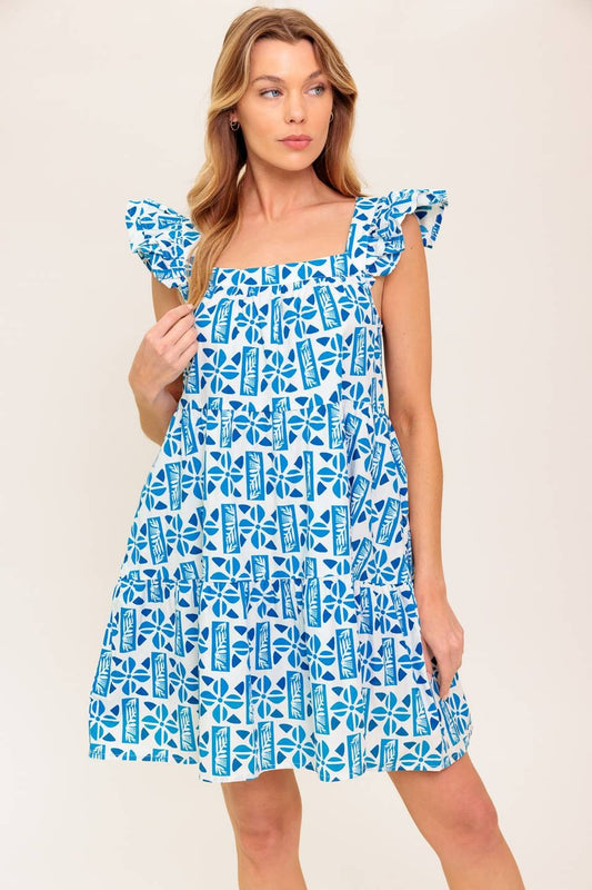 Woman wearing a blue and white geometric print dress with ruffle sleeves