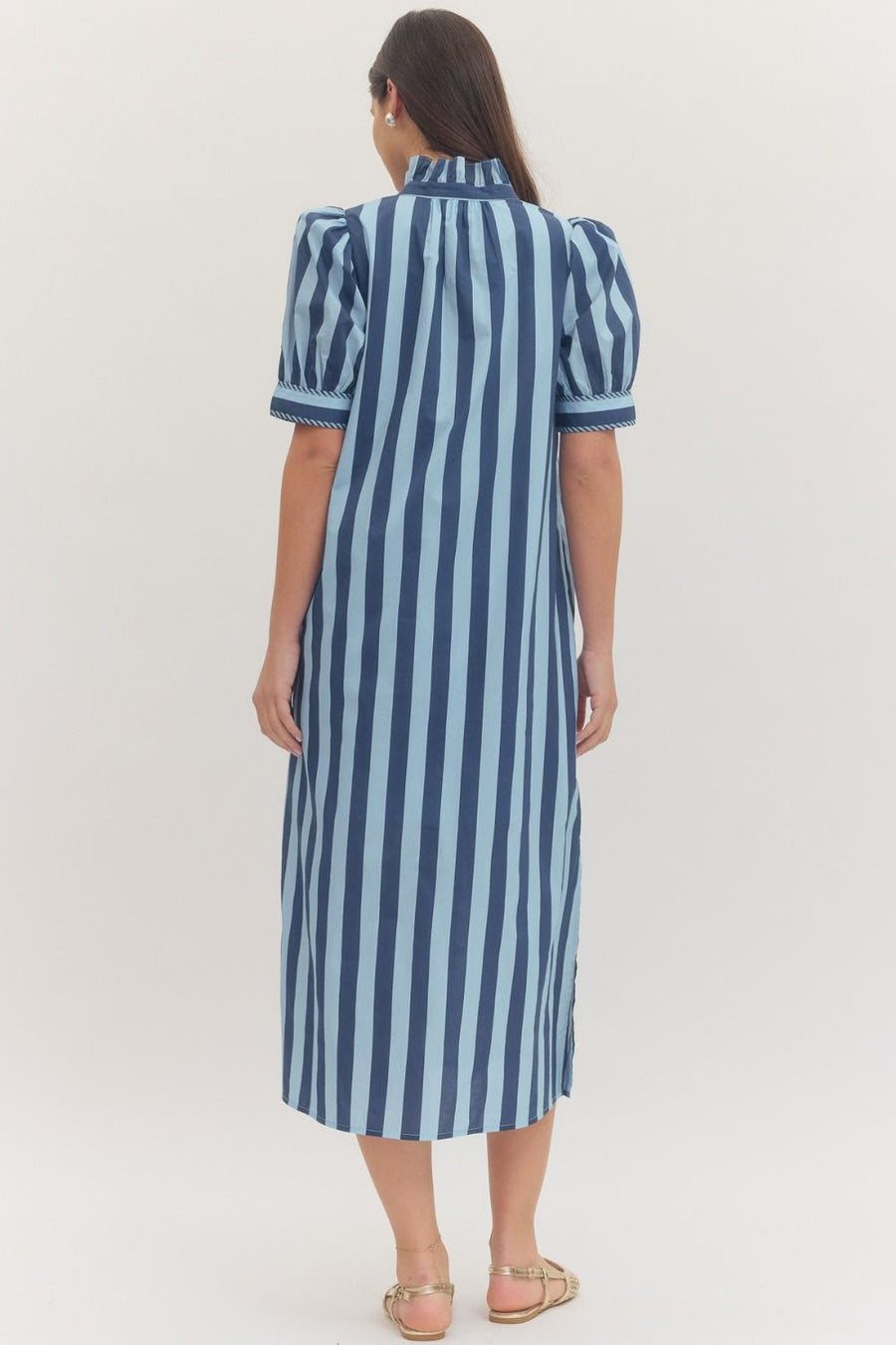 Woman wearing a navy blue and light blue striped dress on a white background