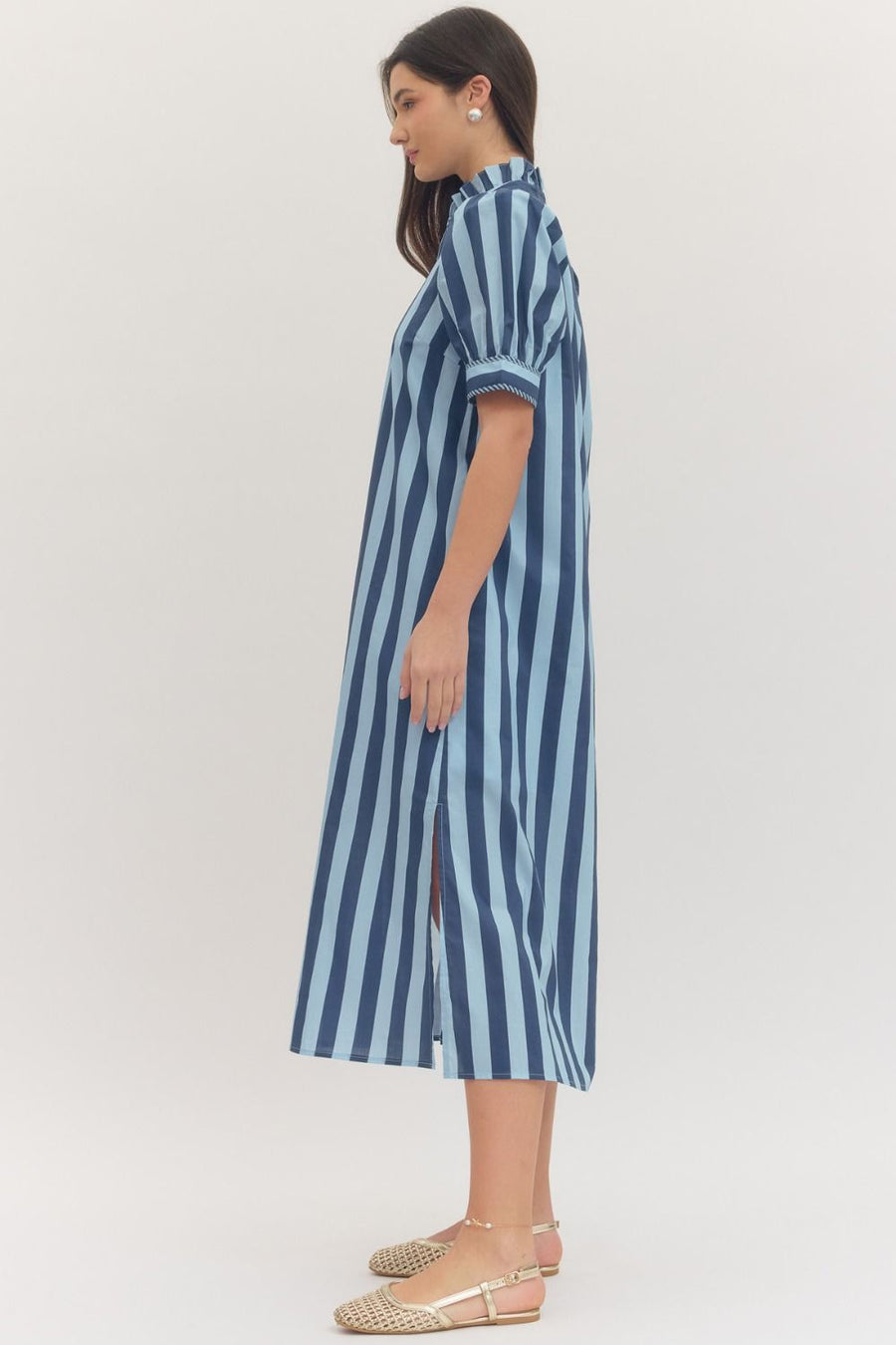 Woman wearing a navy blue and light blue striped dress on a white background