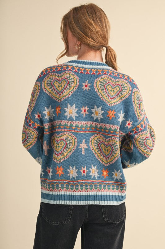 Person wearing a colorful patterned sweater with hearts and stars on a beige background