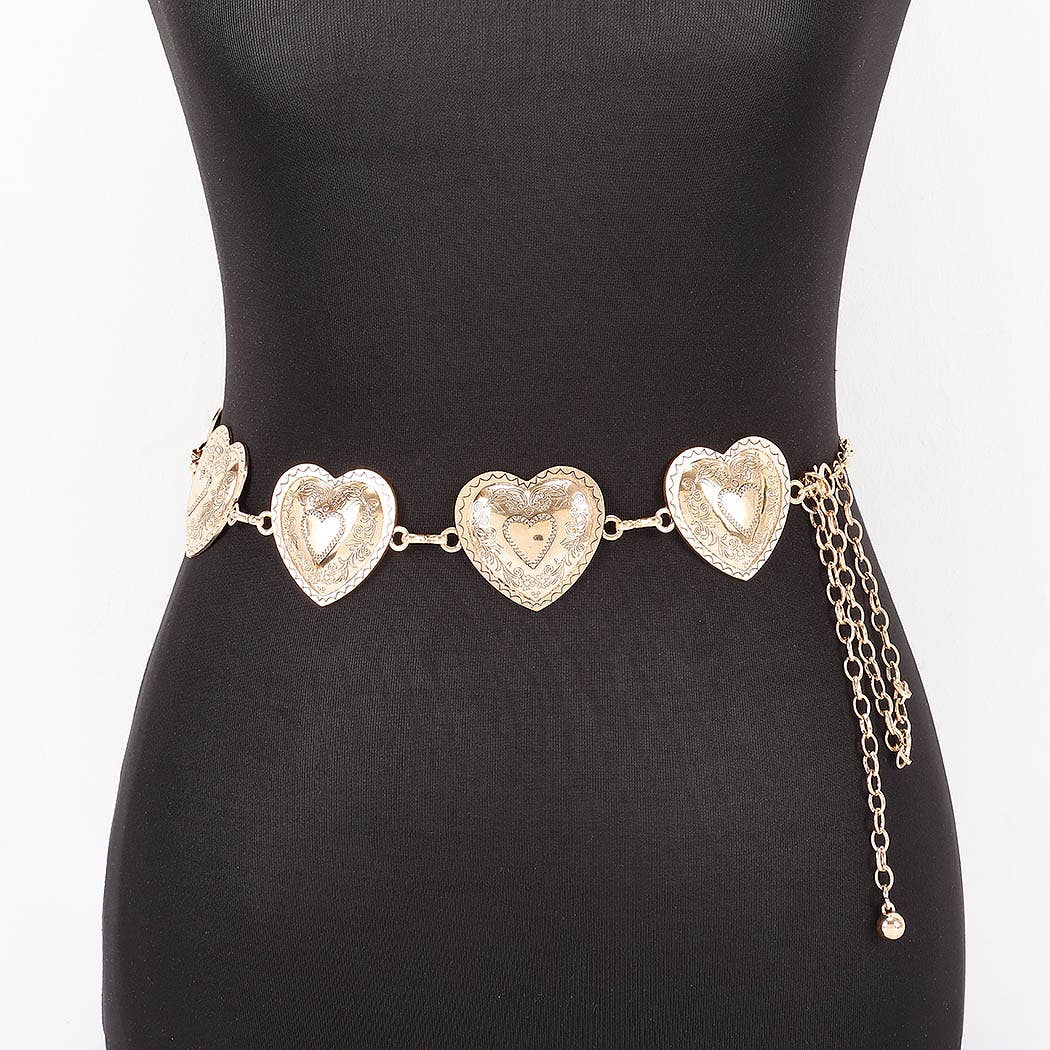 A gold-toned metal chain belt with three large textured heart-shaped links and dangling chain tails, displayed on a black mannequin torso against a white background.