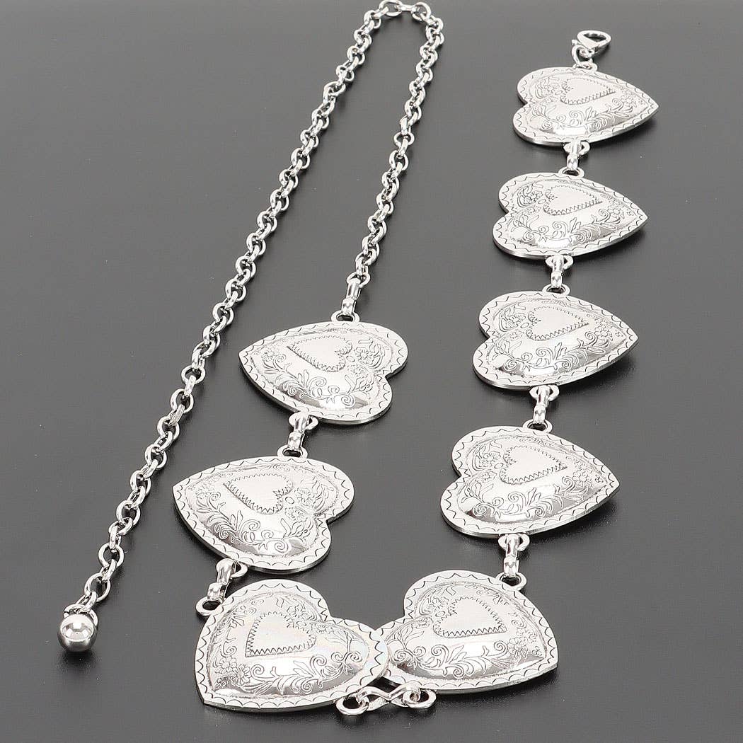 A silver heart-link chain necklace with multiple engraved heart charms, displayed on a dark gray background.
