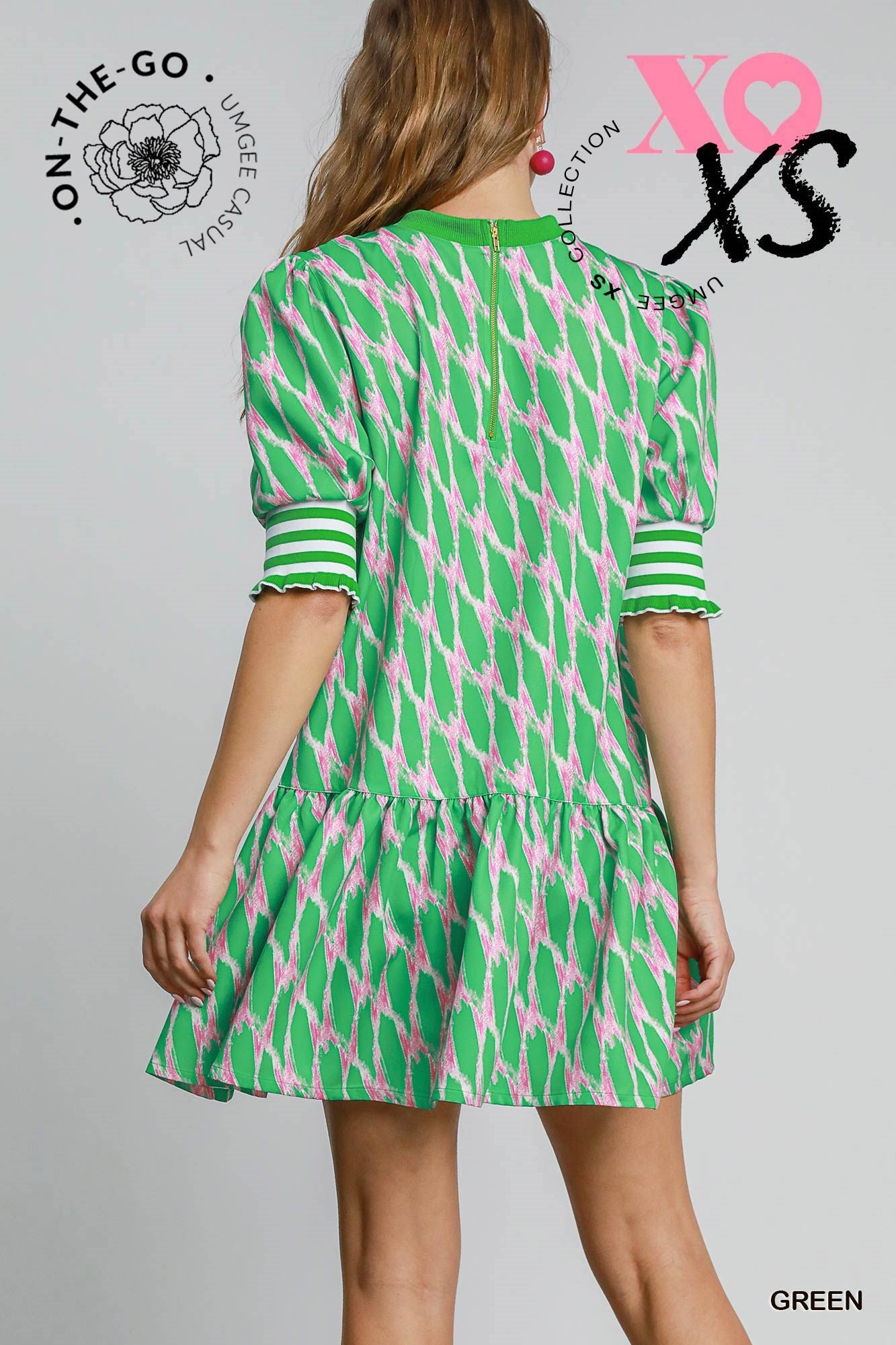Model wearing a vibrant green and pink printed mini dress with puff sleeves and striped cuffs, featuring a tiered skirt and a playful, preppy silhouette.