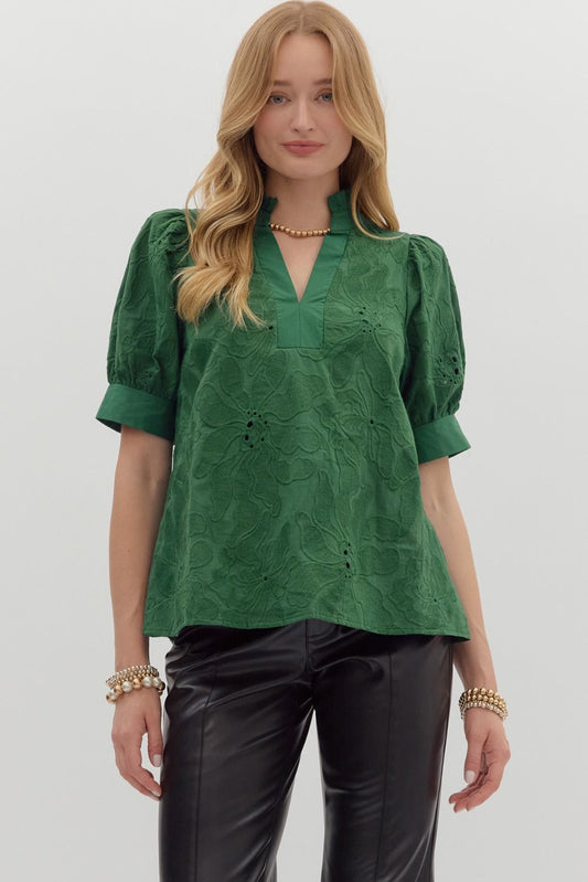 Woman wearing the Emerald Bloom Eyelet Top, a puff sleeve green blouse with floral eyelet embroidery, split neckline, and cuffed sleeves, paired with black leather pants – Milo & Lily Boutique.