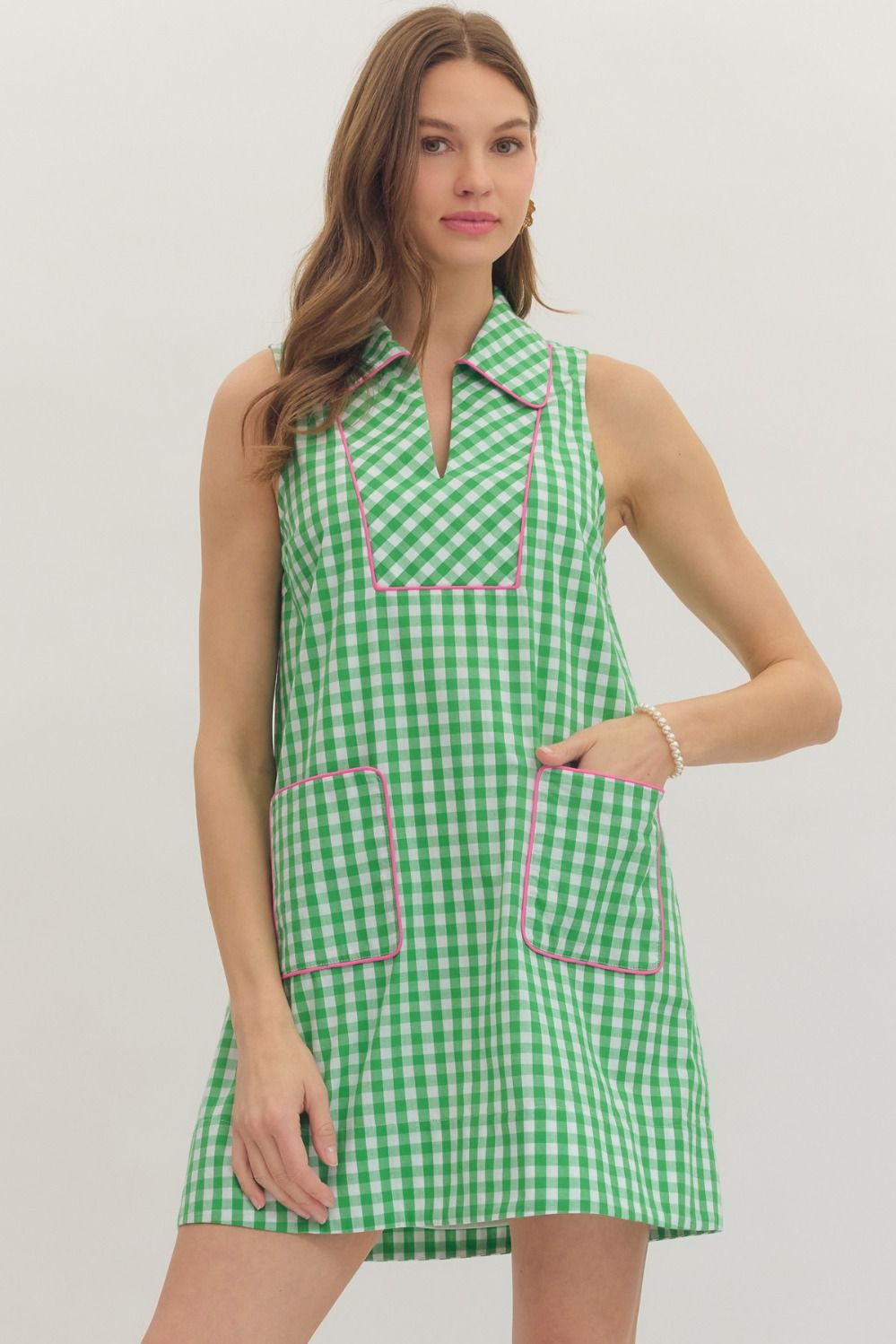 Woman wearing a green checkered dress with pink accents on a white background