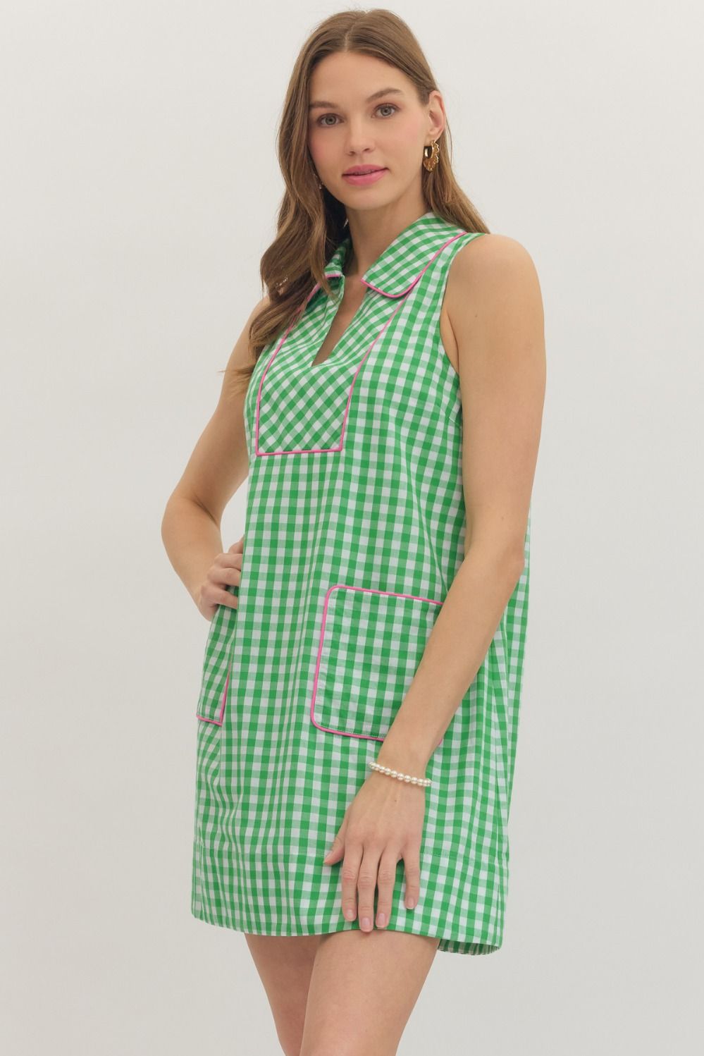Woman wearing a green checkered dress with pink accents on a white background