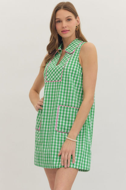 Woman wearing a green checkered dress with pink accents on a white background
