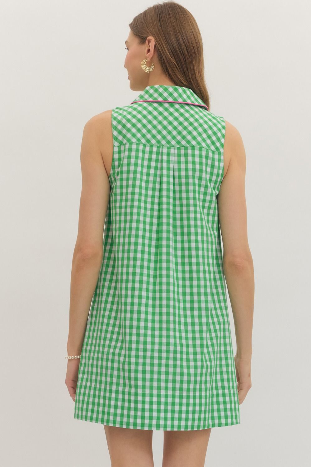 Woman wearing a green checkered dress against a plain background