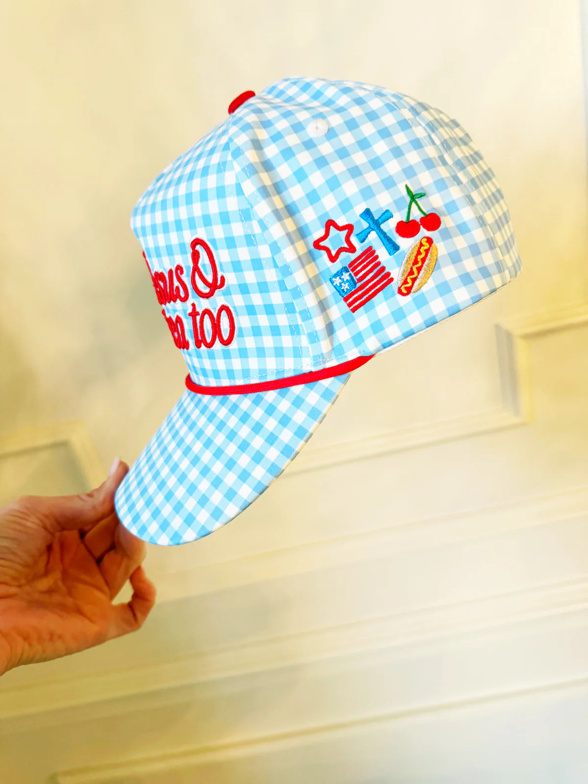 Blue checkered cap with red accents held by a hand on a light wooden surface
