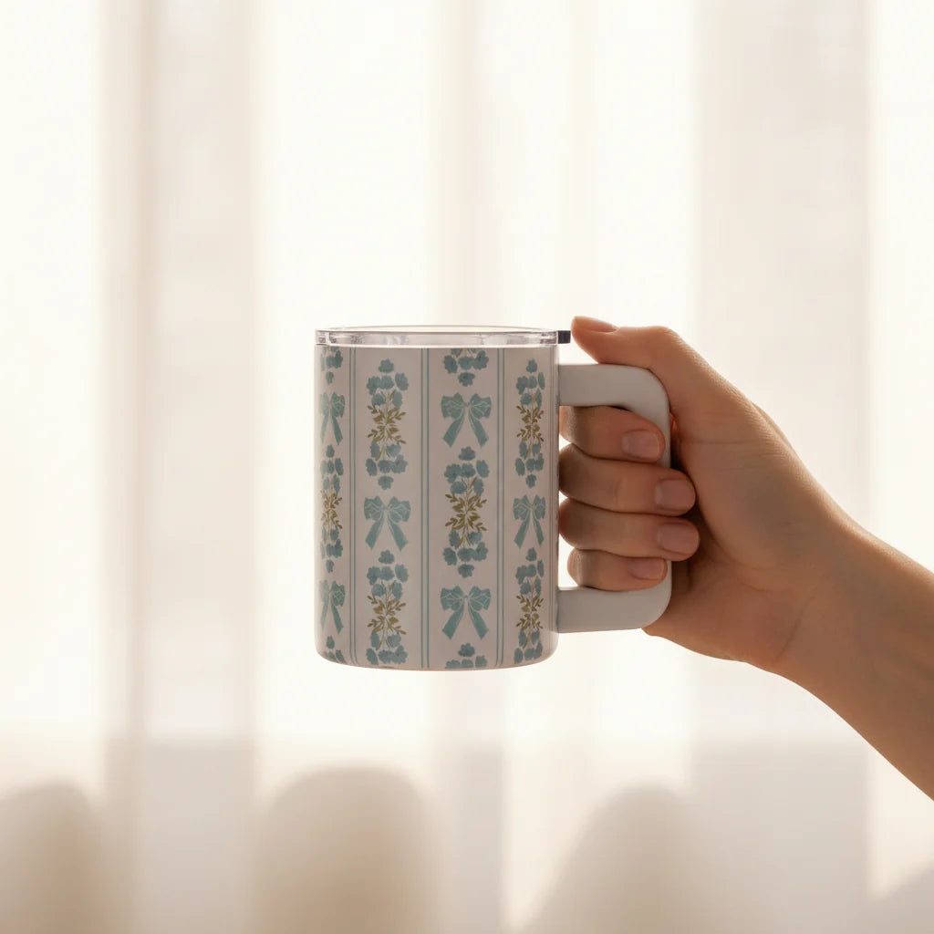 Hand holding a mug with a floral pattern against a soft, blurred background