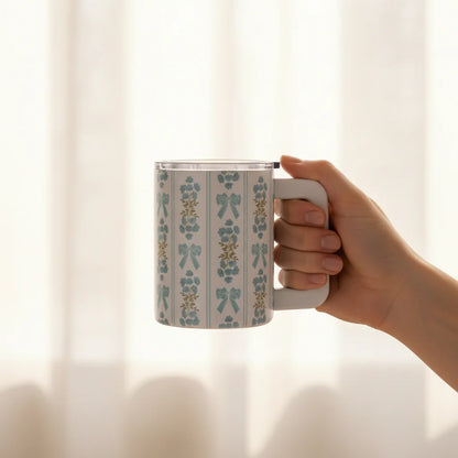 Hand holding a mug with a floral pattern against a soft, blurred background