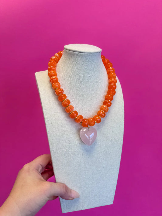 Necklace with a heart-shaped pink pendant on a mannequin bust against a pink background