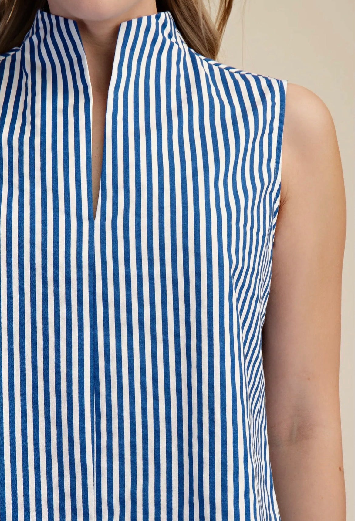 Blue and white striped sleeveless top on a mannequin against a beige background