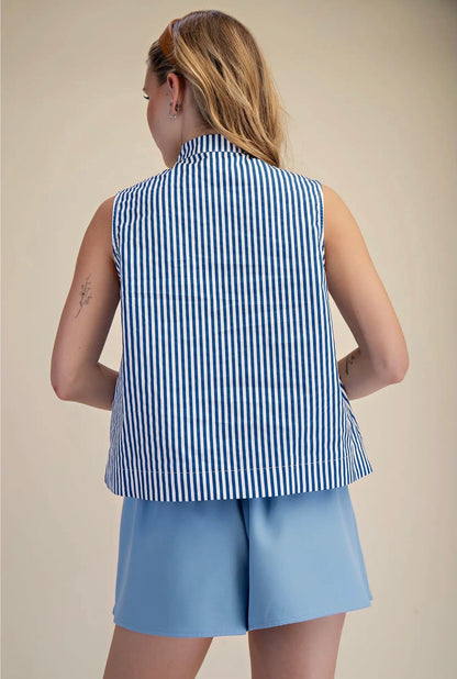 Person wearing a blue and white striped sleeveless top and light blue shorts on a beige background