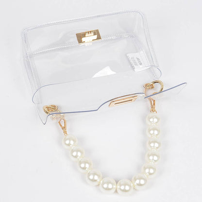Pearl necklace with gold clasp on a clear stand against a white background