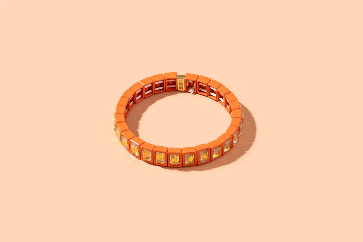 Orange bracelet with square charms on a beige background