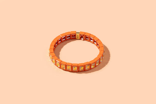 Orange bracelet with square charms on a beige background