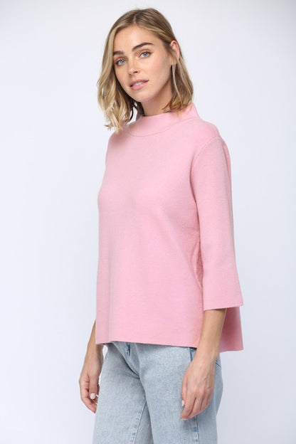 Woman wearing a pink sweater and light blue jeans on a white background