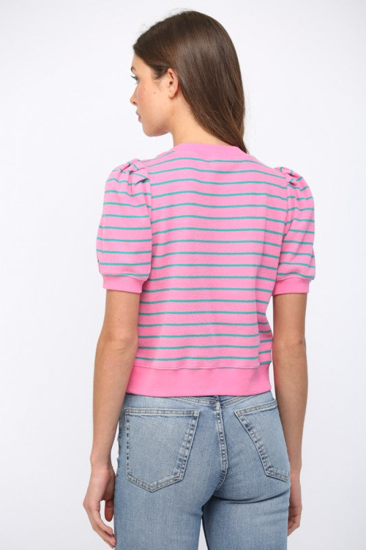 Woman wearing a pink and blue striped shirt with puffed sleeves on a white background