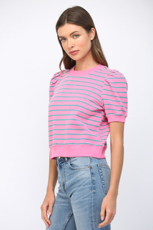 Woman wearing a pink and blue striped sweater with light blue jeans on a white background