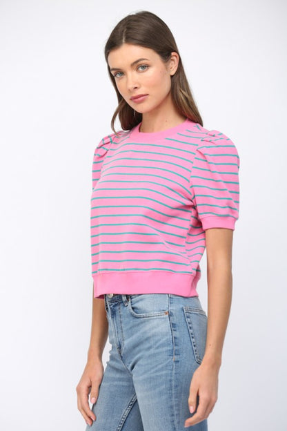 Woman wearing a pink and blue striped sweater with light blue jeans on a white background