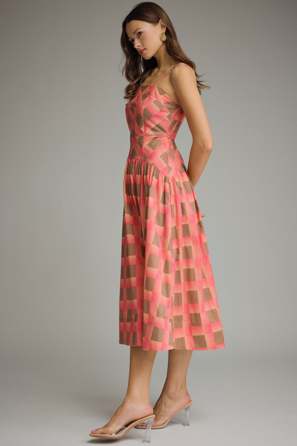 Woman wearing a pink and brown checkered dress on a gray background