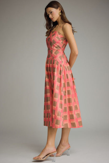 Woman wearing a pink and brown checkered dress on a gray background