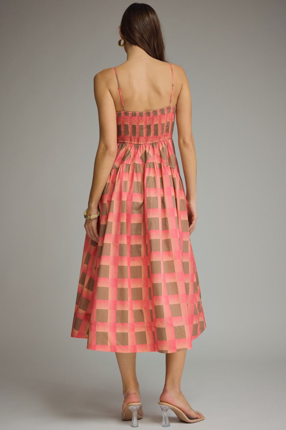 Woman wearing a red and brown checkered dress against a gray background