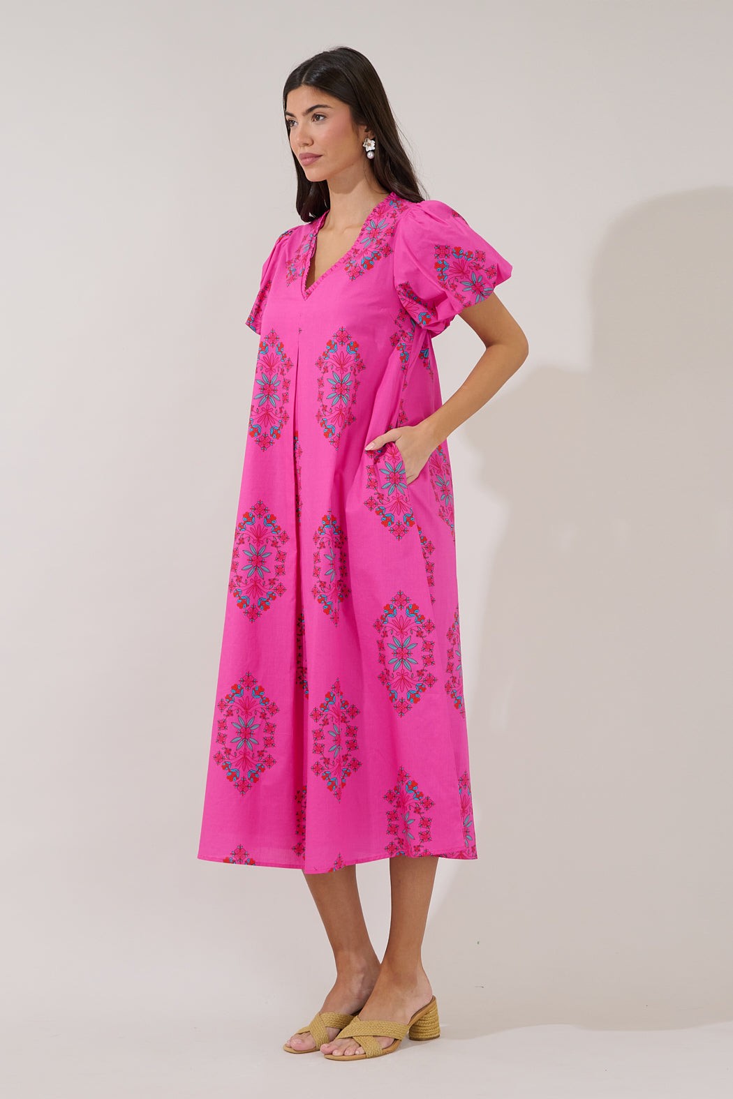 Woman wearing a pink dress with floral patterns on a white background