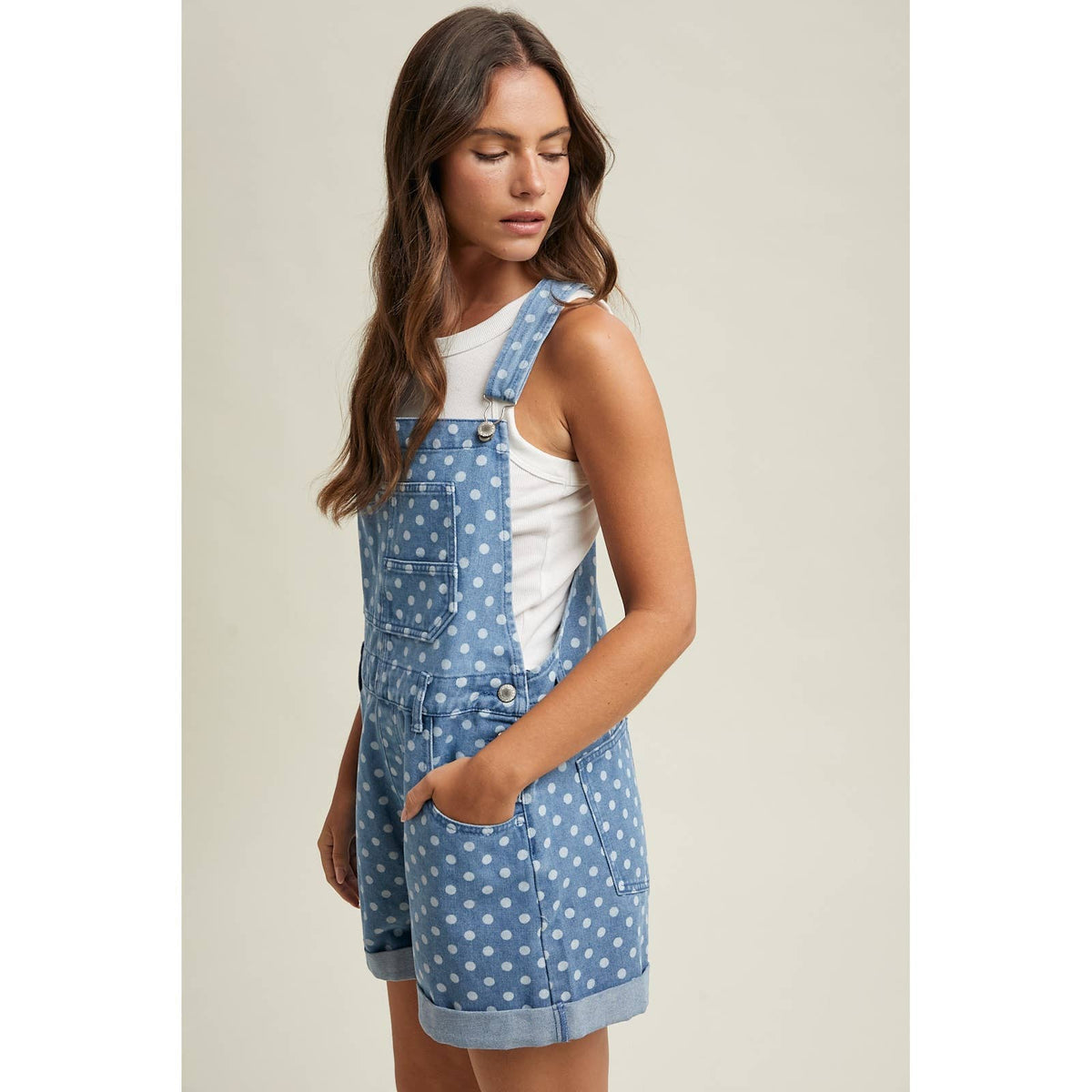 Woman wearing a blue polka dot denim dress against a neutral background