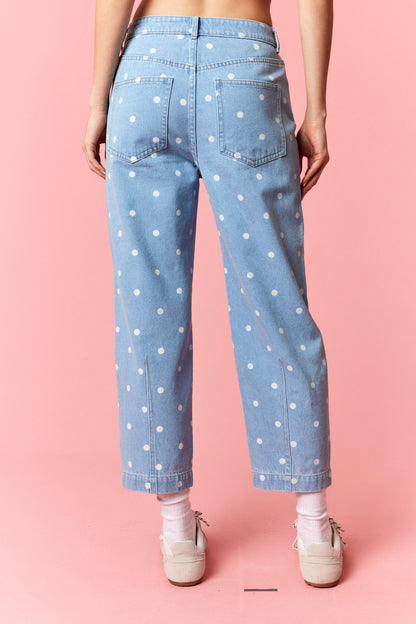 Light blue jeans with white polka dots worn by a person on a pink background