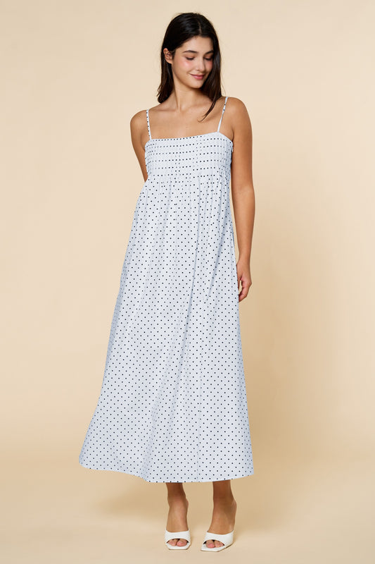 Woman wearing a blue dress with navy polka dots on a beige background