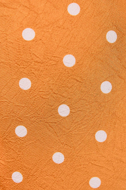 Orange textured fabric with a white polka dot pattern.