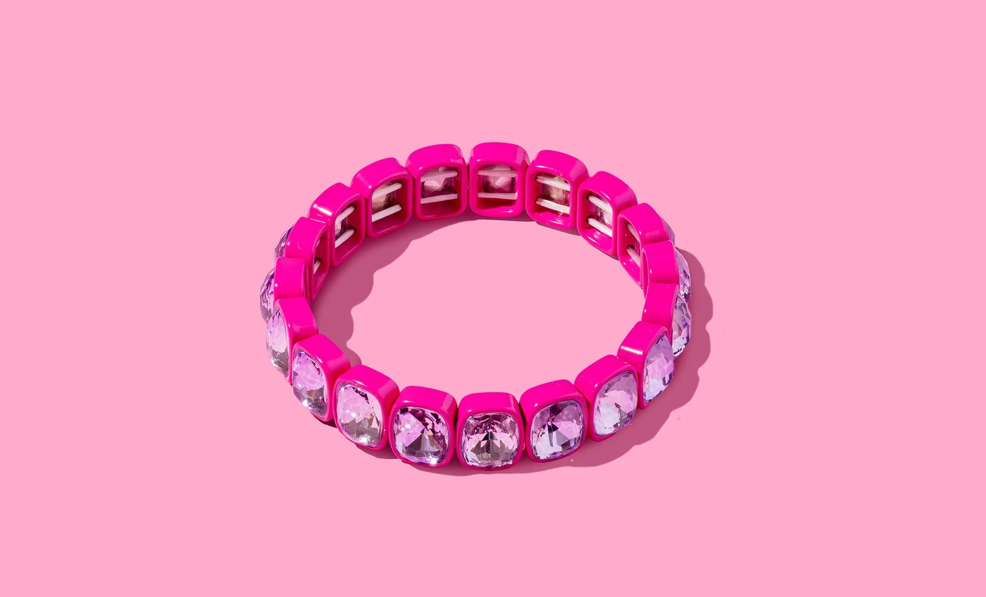 Pink square crystal stretch bracelet with clear gemstones on pink background