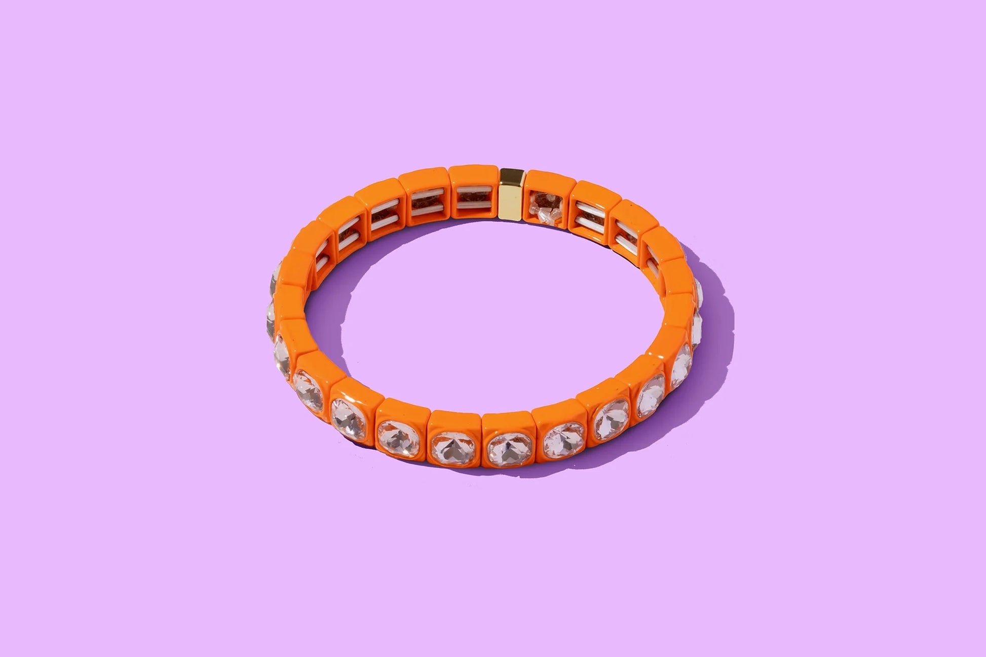 Orange stretch bracelet with clear crystal accents on a purple background